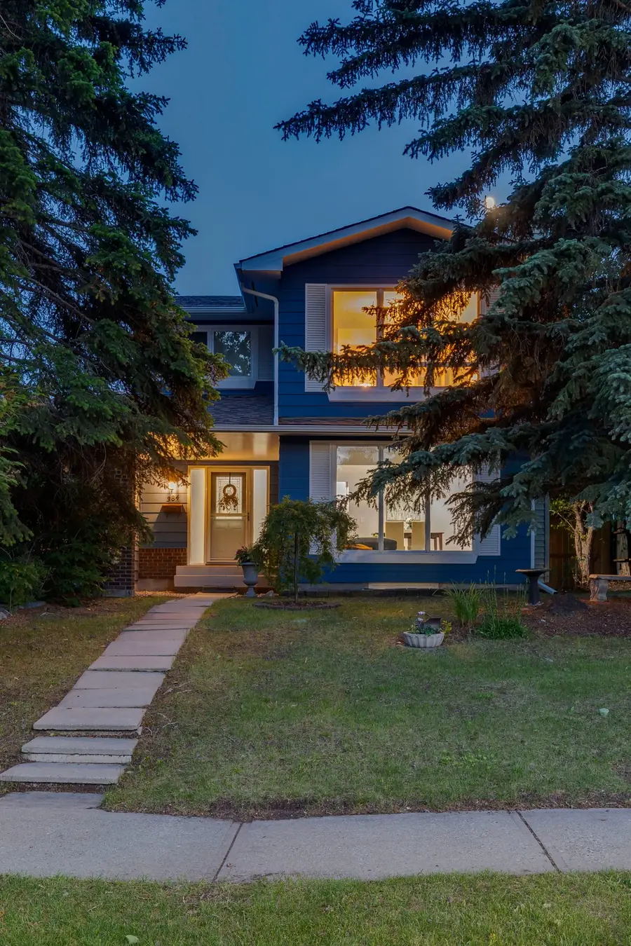 Two-storey Calgary home at twilight framed by spruce trees